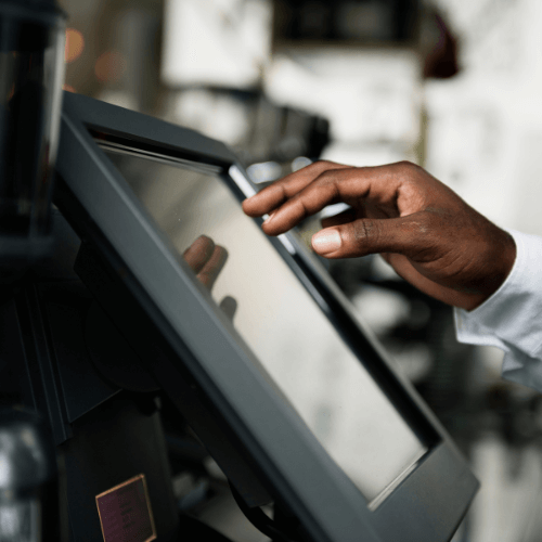 A hand touching a touchscreen point-of-sale system.