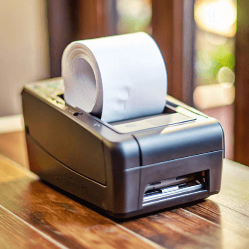 A receipt printer with a roll of paper on a wooden surface.